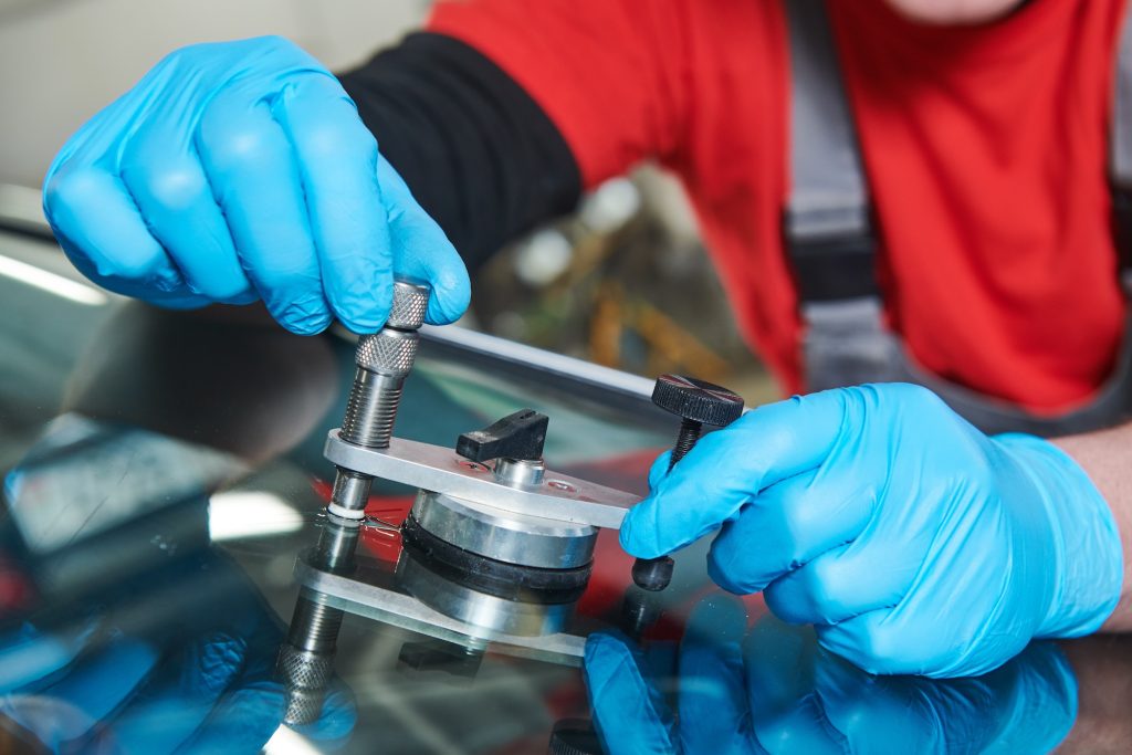 windshield glass repair service. Car Glazier using tools for crack or chip repairing