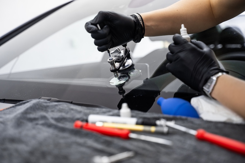 Resin repair on windshield using injector application to restore structural clarity. Windshield crack repair using resin injection. Technician using windshield injector tool to fix bullseye crack